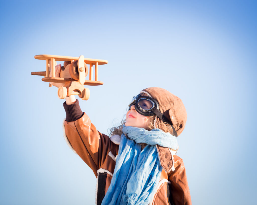 happy,kid,playing,with,toy,wooden,airplane,against,winter,sky
